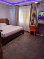 Una habitación de hotel con cama, escritorio y televisor.