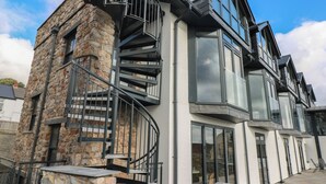 Ein modernes Gebäude mit Naturstein-Fassade, einer Wendeltreppe und großen Fenstern.
