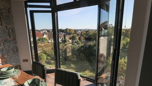 Ein Essbereich mit einem Tisch für zwei Personen, große Fenster mit Blick auf eine Wohngegend.