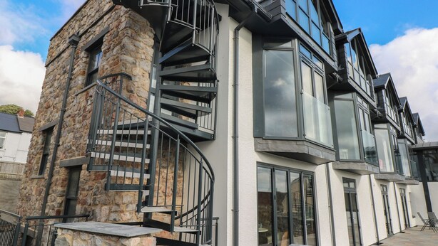 A modern building with a stone facade, a spiral staircase, and large windows. - 10 Brython Place (Tenby)