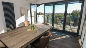 A modern dining area with a wooden table, chairs, and a view through large sliding glass doors to an outdoor patio. - 10 Brython Place (Tenby)