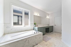 Une salle de bain moderne avec une grande baignoire, une fenêtre et un lavabo.