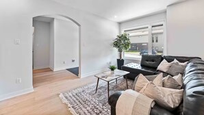 Ett modernt vardagsrum med en svart lädersoffa, ett soffbord och en krukväxt.