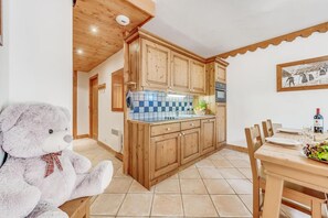 Eine Küche mit Holzschränken, einer Fliesenrückwand und einem Essbereich mit Tisch für zwei Personen.