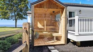 A wooden cabin with a glass door, a small porch, and a view of the sea.
