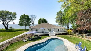 A house with a swimming pool, a deck, and a view of the ocean.