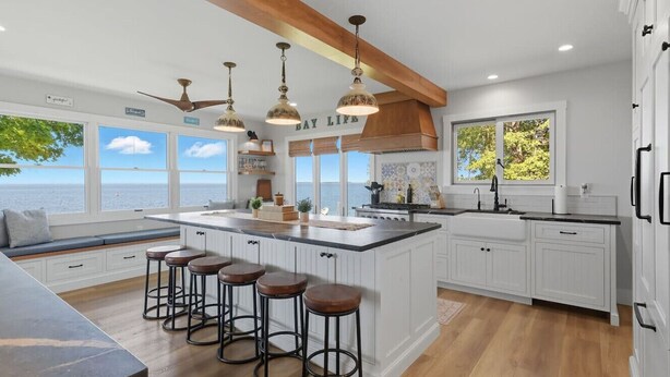 A modern kitchen with a large island, bar stools, and a view of the ocean.
