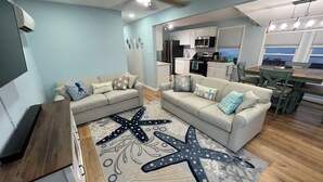 A living room with two sofas, a starfish rug, and a ceiling fan. - Back Bay Getaway (Wildwood)