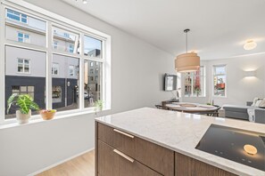 Una cocina moderna con un ventanal grande, un horno empotrado y una zona de comedor con una mesa redonda.