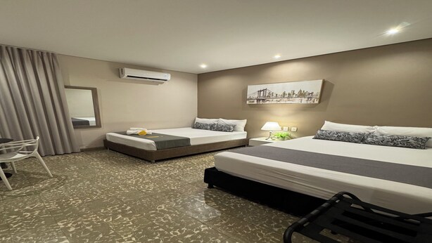 A hotel room with two beds, a desk, a chair, an air conditioner, and a cityscape painting on the wall. - Cómoda habitación Twin en Manga cerca al Centro (Cartagena)