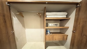 A walk-in closet with wooden shelves, a hanging rod, and a small shelf with a device and a bottle. - Cómoda habitación Twin en Manga cerca al Centro (Cartagena)