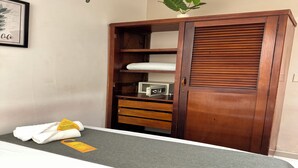 Une pièce bien rangée, avec une armoire en bois, un four à micro-ondes et une petite plante posée sur le dessus.