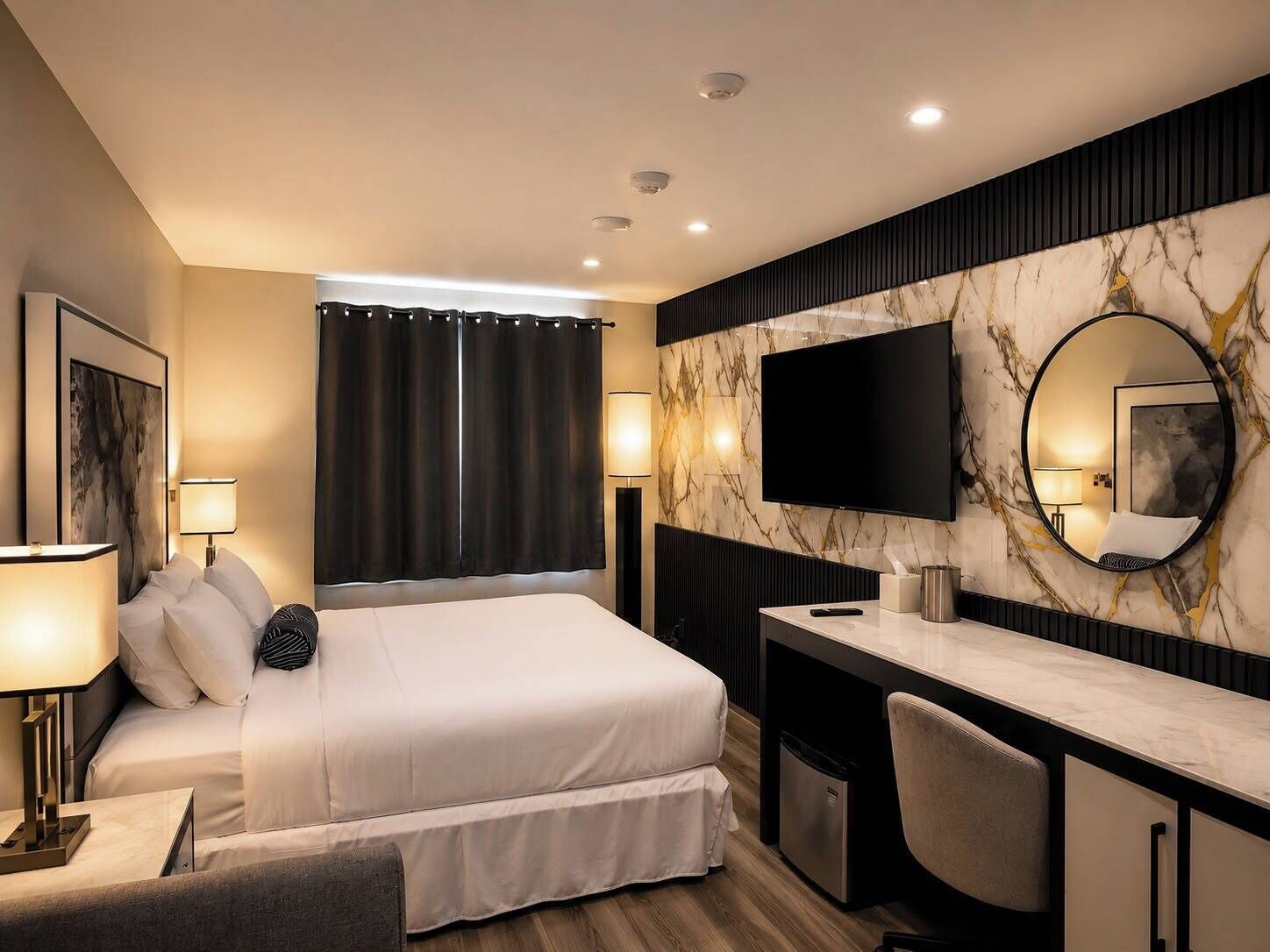 A hotel room with a bed, desk, chair, TV, and a mirror.