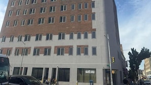 Un edificio de varios pisos con fachada plana, ventanas grandes y acceso en esquina.