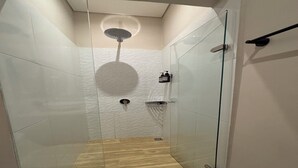 Una ducha moderna con puerta de vidrio, suelo de madera y pared con textura.