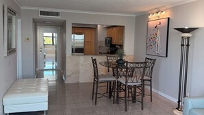 A spacious living area with a dining table, chairs, a sofa, and a coffee table. - Charming condo in fantastic St. Petersburg Beach, with waterfront, sunset views (St. Petersburg)