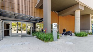A modern building entrance with a covered area, a sign with the number 5176, and a parked scooter. - Complete Studio With Self Check-in Cob0710 (São Paulo)