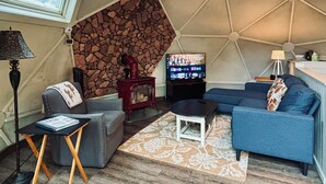 A cozy living room with a stone wall, a fireplace, a television, and comfortable seating.