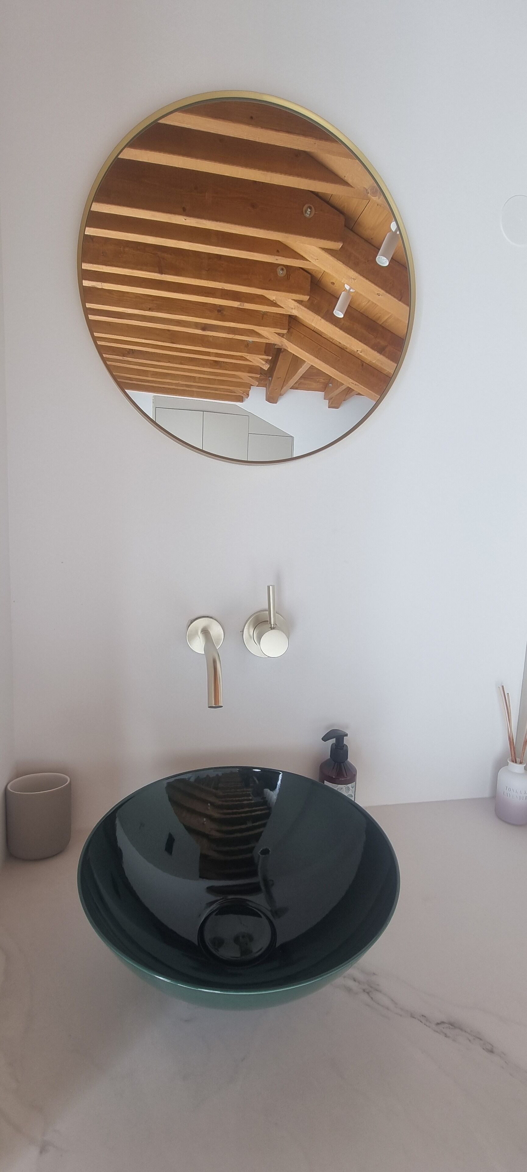 Une salle de bain avec un miroir rond, un lavabo en verre et des toilettes.