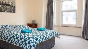 Een slaapkamer met een bed, een dressoir en een raam.