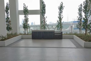 A spacious indoor area with a view of a bridge and water. There are planters with greenery and a seating area with a bench. - UCSI Residence 2 By UCSI Hotels (Kuala Lumpur)