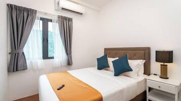 Quarto de hotel com cama, mesa de cabeceira, luminária e aparelho de ar condicionado.