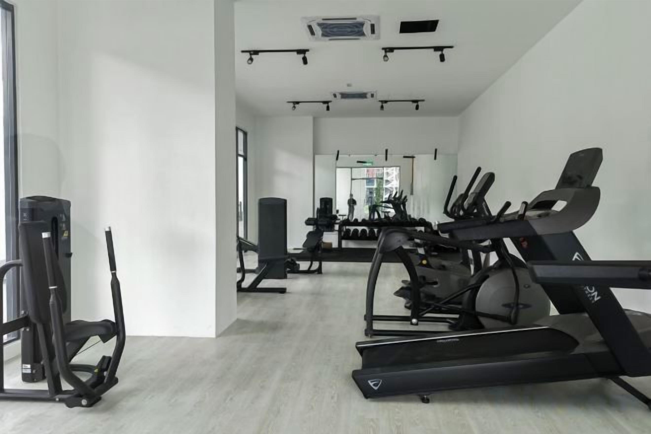 Uma academia com esteiras, elípticos e equipamentos de musculação.
