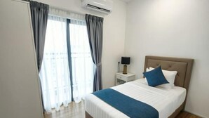 Une chambre d’hôtel avec un lit, des rideaux, un climatiseur, une table de chevet et une lampe.
