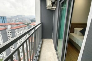 Un balcón con vista a la ciudad, una cama con cabecera y una ventana con cortina.