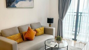 Un salon moderne avec un canapé, une table basse en verre et une lampe.