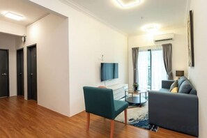 Una sala de estar moderna con un sofá, una silla, un televisor y un ventanal con cortinas.