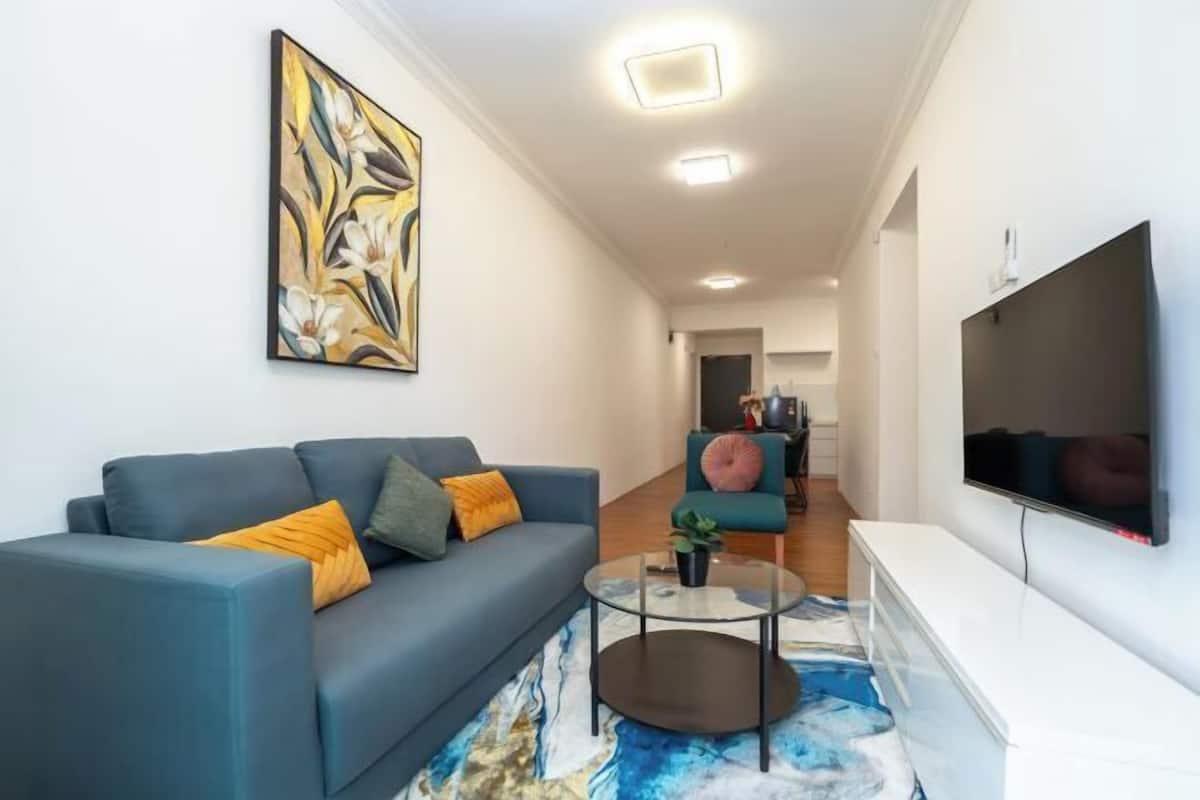 A modern living room with a sofa, coffee table, and artwork on the wall.