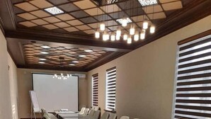 Un salón de conferencias con una larga mesa, sillas, una pantalla de proyector y una pizarra.