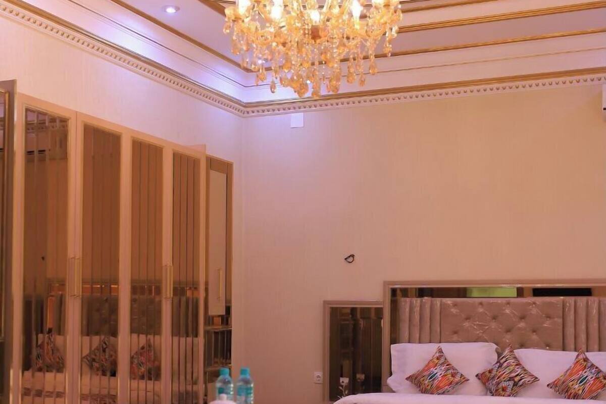 Ein luxuriöses Schlafzimmer mit einem großen Bett, einer Chandelierleuchtre und einer Sitzecke mit Sesseln und einem Tisch.