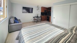 A compact bedroom with a bed, a sofa, a small dining table, and a kitchenette. - Modern studio close to Barrio Italia (Santiago)