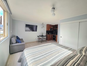 A compact bedroom with a bed, a sofa, a small dining table, and a kitchenette. - Modern studio close to Barrio Italia (Santiago)