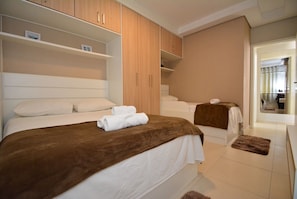 Un dormitorio con dos camas, un armario de madera y un baño con bañera.
