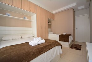 A hotel room with two beds, wooden cabinets, a wardrobe, and a bathroom.