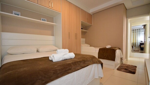 Une chambre avec deux lits, une armoire en bois et une salle de bain avec une baignoire.