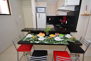 A compact kitchen with a microwave, refrigerator, and black countertop.