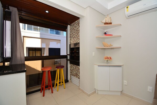 A compact kitchen with a window, two stools, and a white cabinet.
