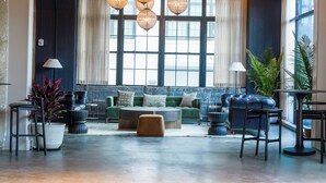 A spacious lobby with a high ceiling, large windows, and a seating area with sofas and chairs.