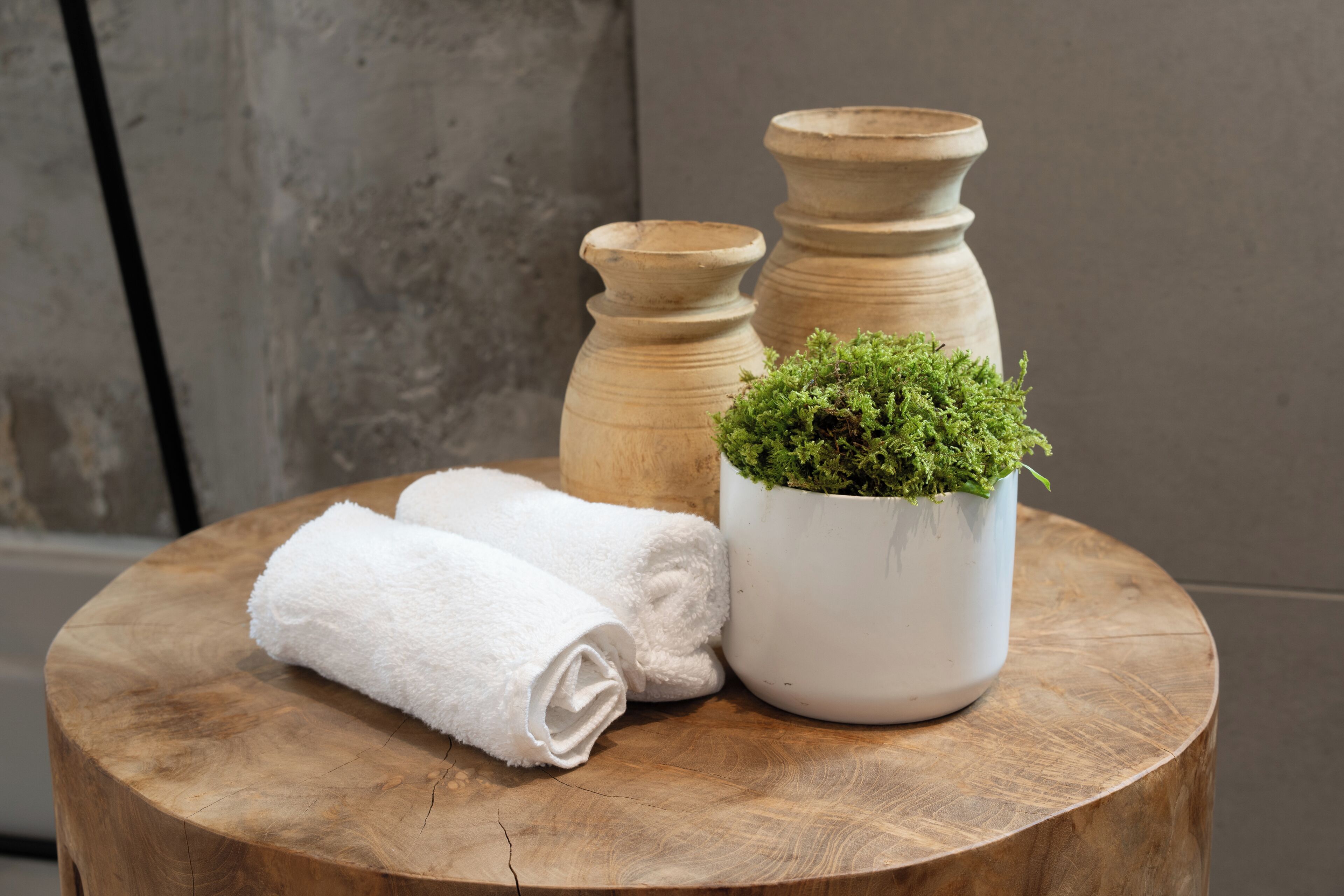 Una mesa redonda de madera con un paño blanco y una planta en maceta.