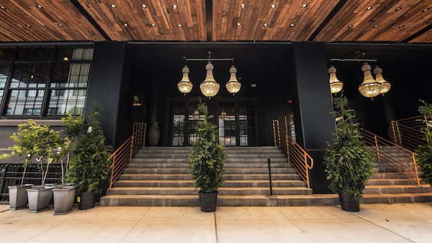 A building entrance with a wooden ceiling, large windows, and a staircase with railings.