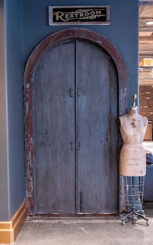 A wooden wardrobe with a hanging robe and slippers, a coffee machine, and a small refrigerator. at Sela V Hotel