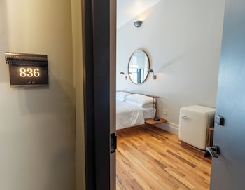 A modern bathroom with a freestanding bathtub, a large mirror, and a view of the city through a window. at Sela V Hotel