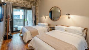 A hotel room with two beds, a large mirror, a ceiling fan, and a view of the outside.