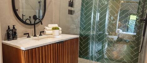 Un baño moderno con tocador de madera, un espejo grande y cabina de ducha de vidrio.