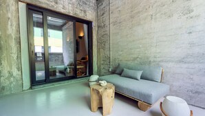 A modern interior with a sofa, a small wooden stool, and a round white ottoman.