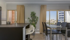 A modern kitchen with a dining area, large windows, and a view of the city.